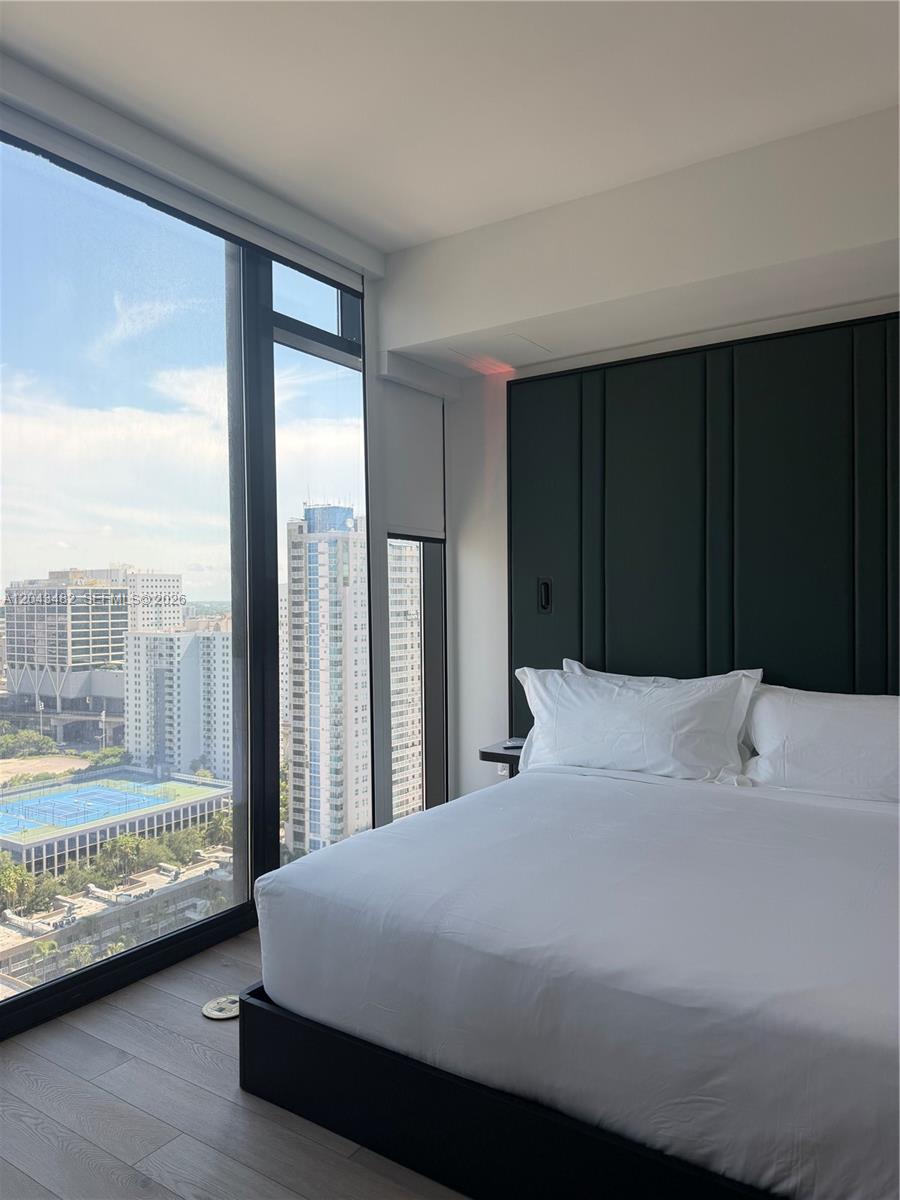 A bedroom features a platform bed against a dark paneled wall beside floor-to-ceiling windows — 20 NE 11th St # 4902, Miami FL 33132, MIAMI, FL