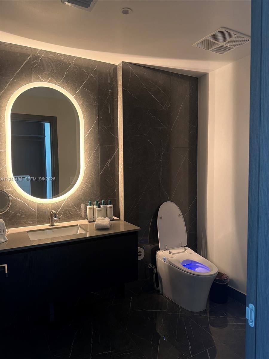 A modern bathroom features dark marble walls, a floating vanity, and a lighted toilet — 20 NE 11th St # 4902, Miami FL 33132, MIAMI, FL