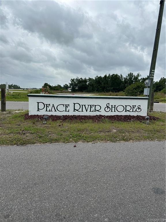 A white monument sign with black lettering reads Peace River Shores near a paved road — 145 BODINE STREET, PUNTA GORDA, FL