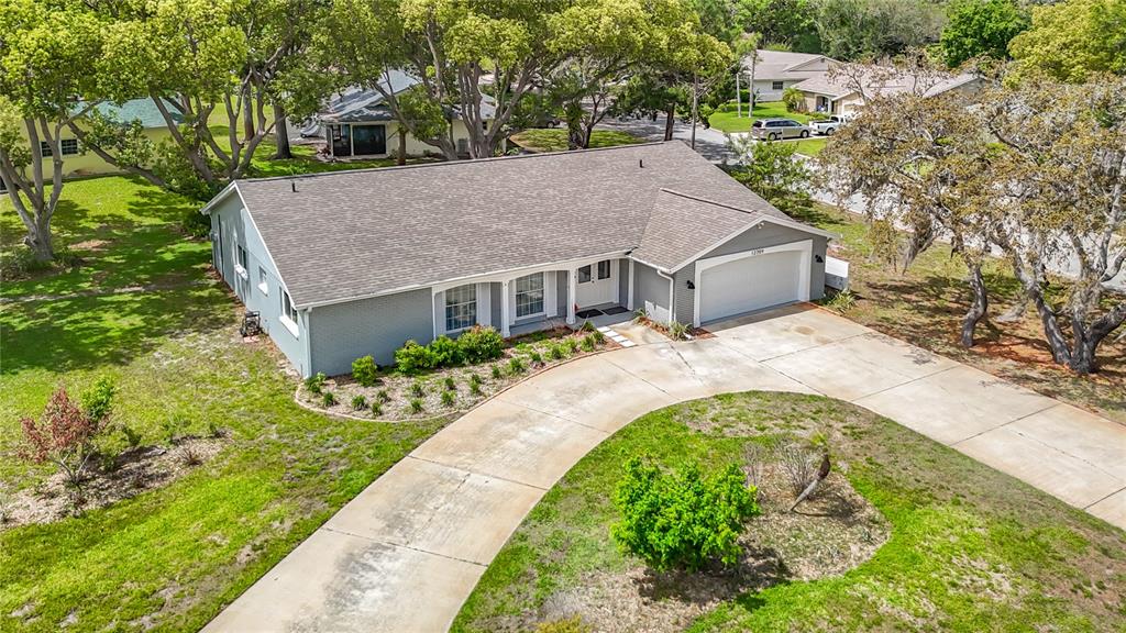 An aerial view of a gray, single-story house with a shingled roof and concrete driveway — 12709 CASTLEBERRY COURT, HUDSON, FL