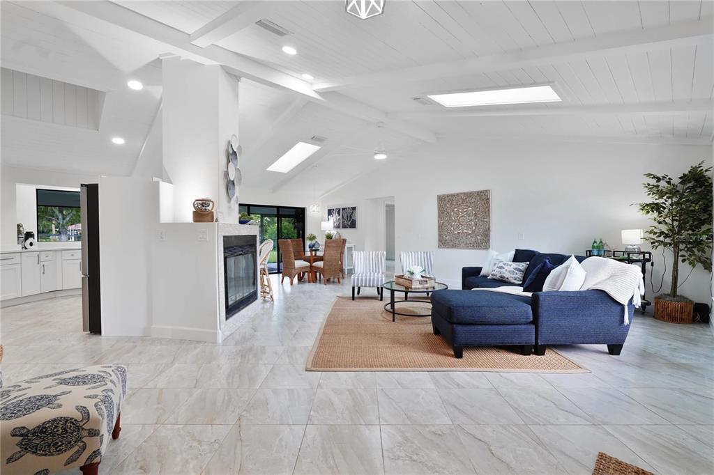 A bright, open-concept living and dining area features white vaulted ceilings, tile floors, and a fireplace — 5012 S DEEP WATER POINT, HOMOSASSA, FL