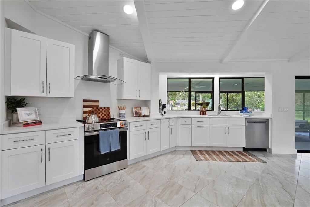 A bright, modern kitchen features white cabinets, stainless steel appliances, and light-colored tile flooring — 5012 S DEEP WATER POINT, HOMOSASSA, FL