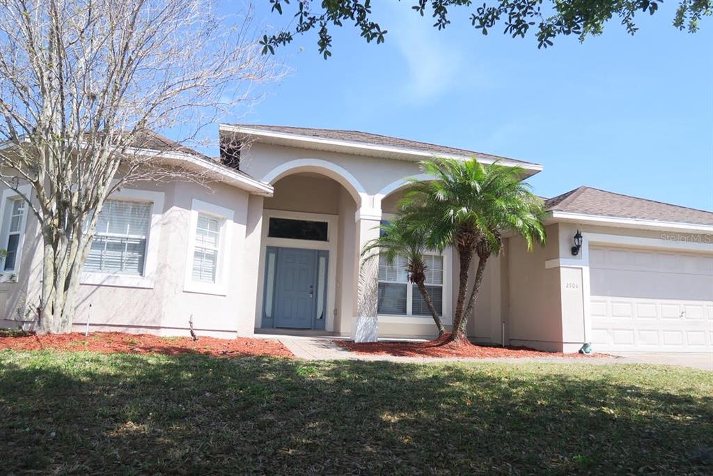 A single-story house with a beige stucco exterior, arched entryway, and a two-car garage — 2906 SWEETSPIRE CIRCLE, KISSIMMEE, FL