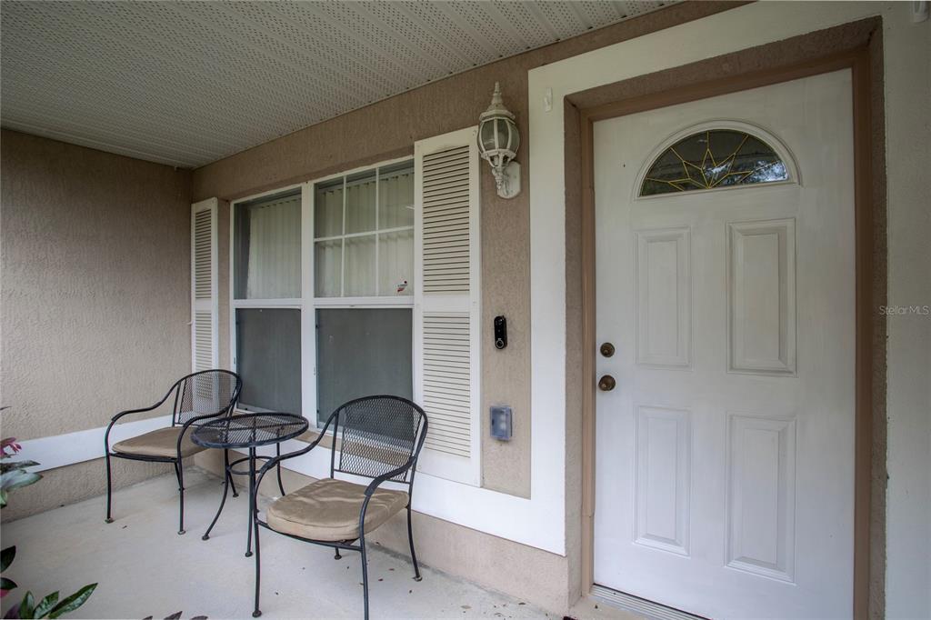 A white front door and two metal chairs sit on a covered concrete porch — 1495 3RD STREET, ORANGE CITY, FL