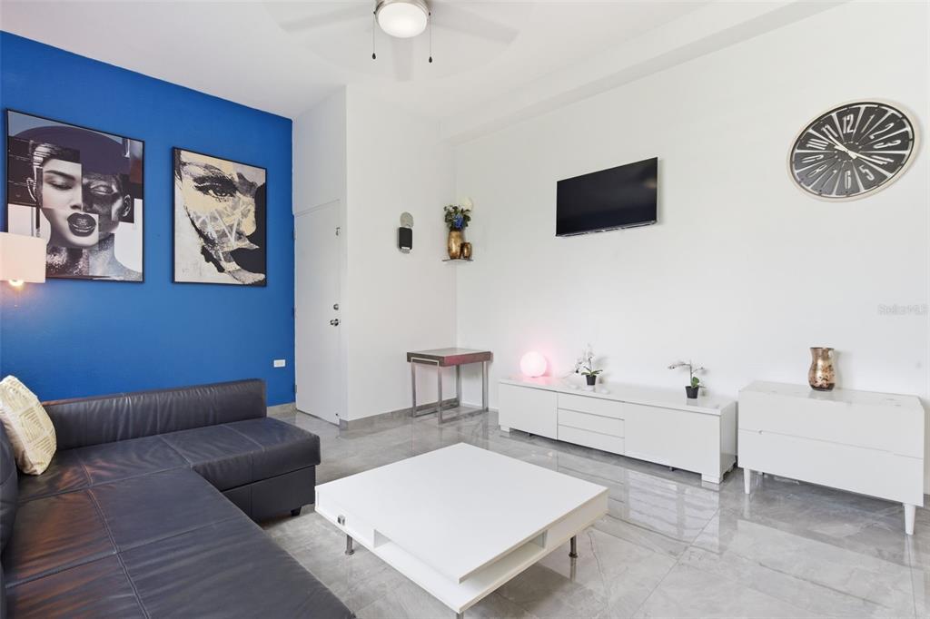 A living room features a dark leather sofa, white furniture, and a blue accent wall — 56 CALLE F KRUG CONDADO UNIT PH-2, SAN JUAN, PR