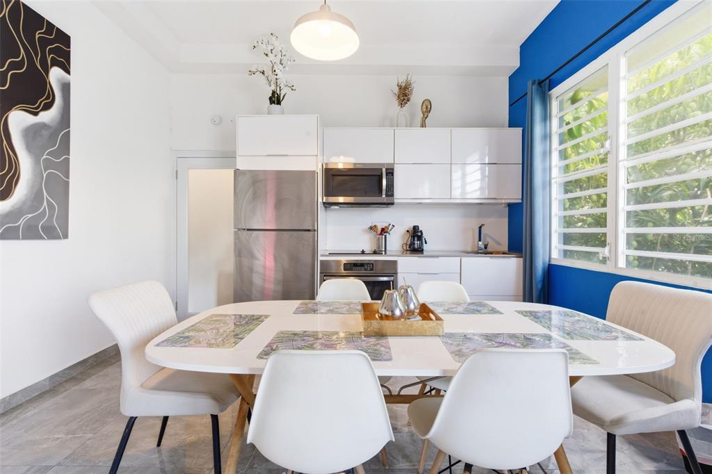 A dining area with a white table and chairs sits in front of a modern kitchen — 56 CALLE F KRUG CONDADO UNIT PH-2, SAN JUAN, PR