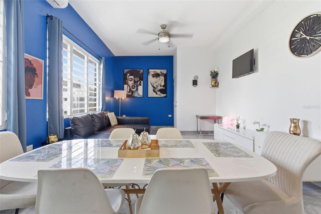 A dining area with a white table and chairs sits in front of a blue-walled living room — 56 CALLE F KRUG CONDADO UNIT PH-2, SAN JUAN, PR