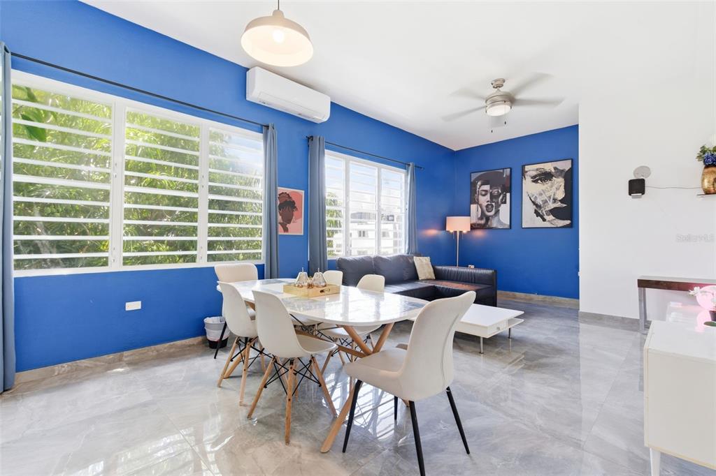 A dining area and living room with blue walls, tile floors, and large windows — 56 CALLE F KRUG CONDADO UNIT PH-2, SAN JUAN, PR