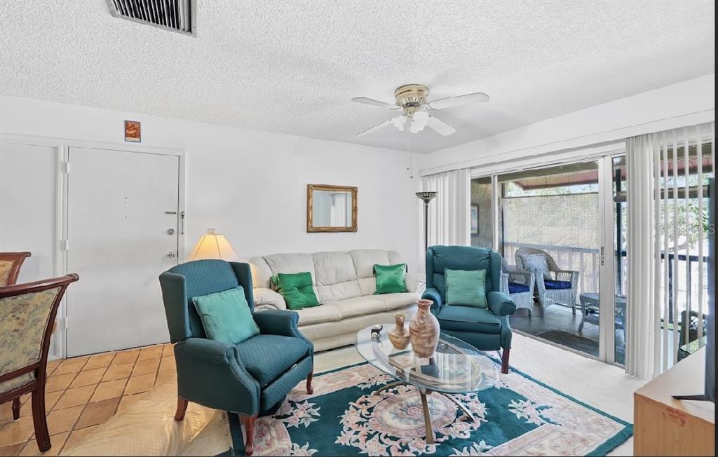A living room features a white sofa, two teal armchairs, a glass coffee table, and balcony — 3853 S LAKE DRIVE UNIT 165, TAMPA, FL
