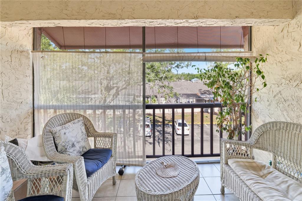 A covered balcony features wicker furniture, tile flooring, and a view of a parking lot — 3853 S LAKE DRIVE UNIT 165, TAMPA, FL