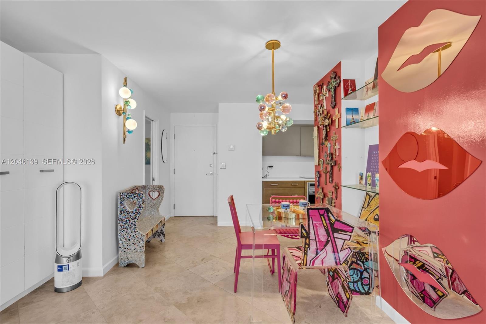 A dining area features a glass table, colorful chairs, a chandelier, and a red wall — 6917 Collins Ave # 404, Miami Beach FL 33141, MIAMI BEACH, FL