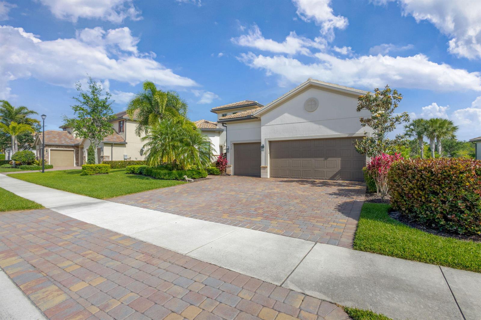 A suburban house features a paved driveway, a three-car garage, and manicured landscaping — 532 Sonoma Isles Circle, Jupiter FL 33478, JUPITER, FL