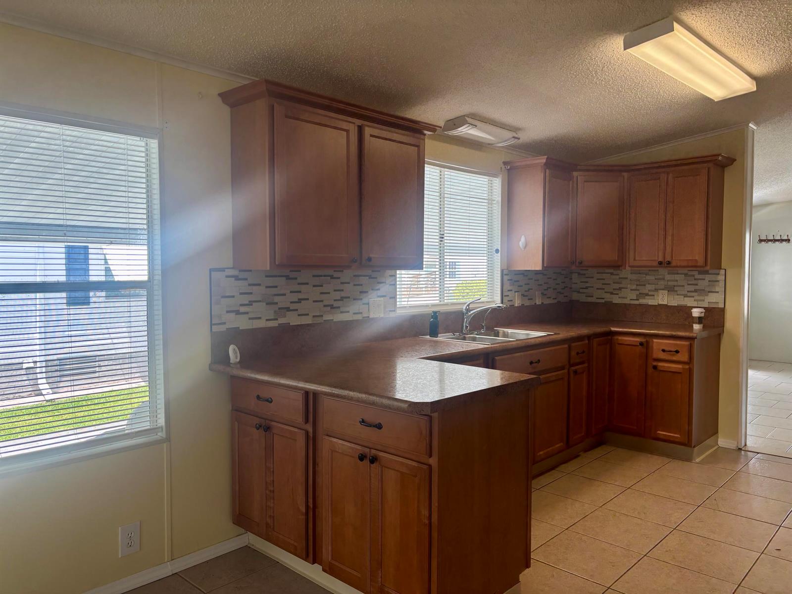 A kitchen with wood cabinets, tiled backsplash, laminate countertops, and tile flooring — 1586 SW 35th Circle, Okeechobee FL 34974, OKEECHOBEE, FL