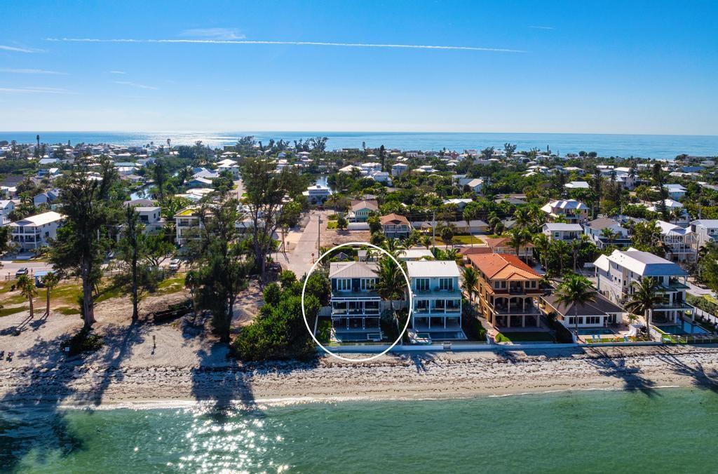 An aerial view of a backyard pool and spa overlooking a beach and the ocean — 915 N SHORE DRIVE, ANNA MARIA, FL