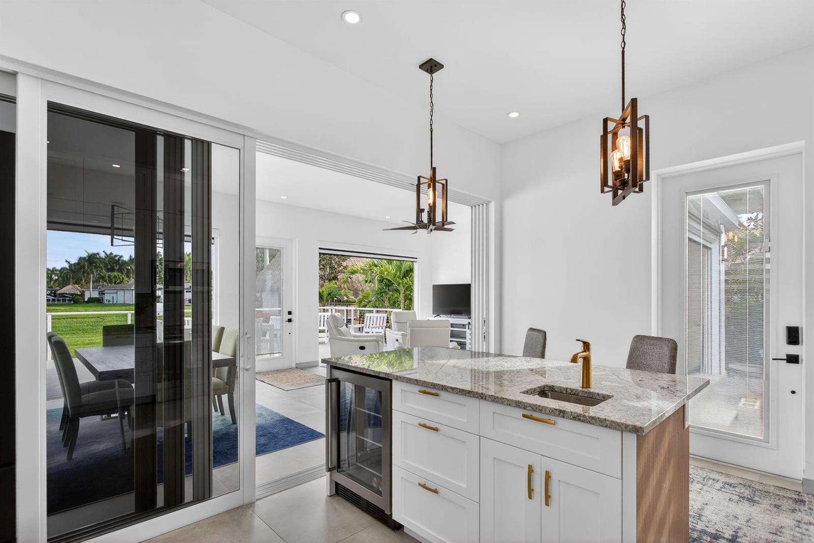A kitchen island with a wine cooler and sink overlooks a patio through sliding doors — 633 N Cortez Drive # 633, Margate FL 33068, MARGATE, FL
