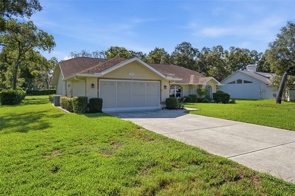 A single-story house with a two-car garage and a concrete driveway sits on a lawn — 192 PRESTON HOLLOW DRIVE, SPRING HILL, FL