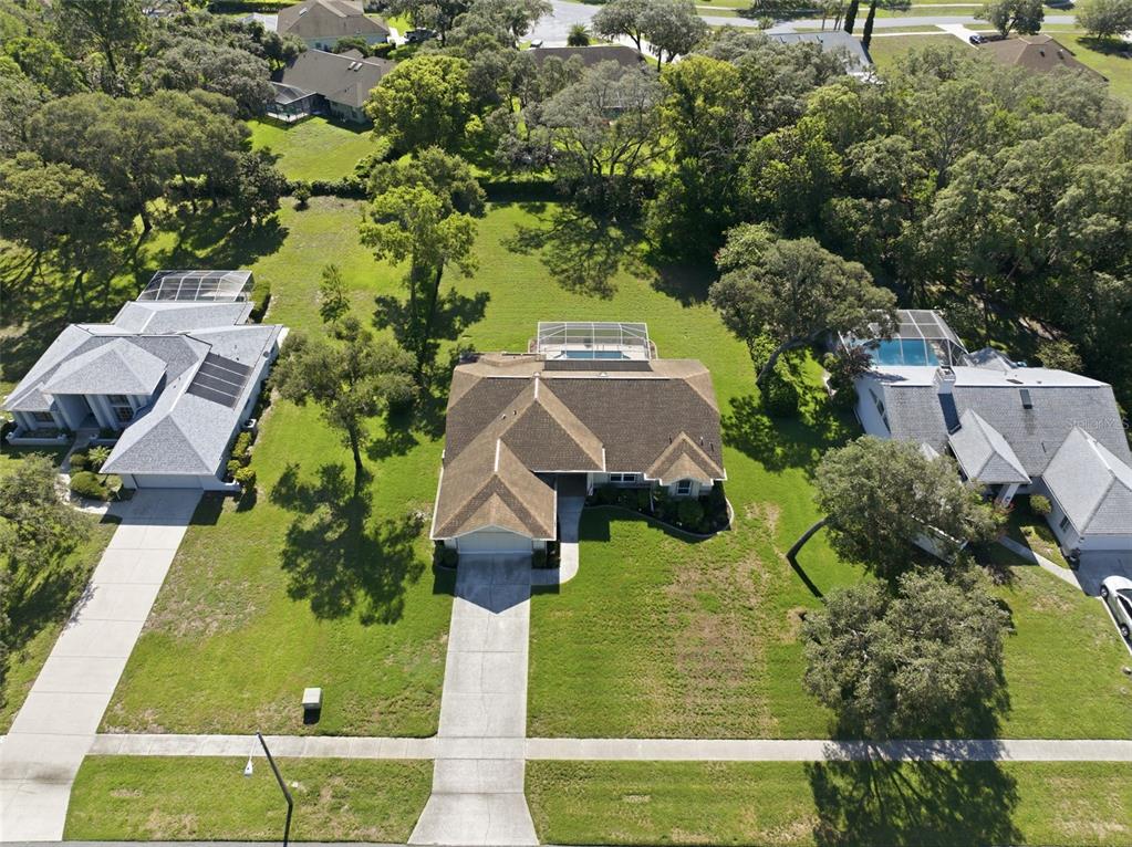 An aerial view shows three suburban houses with pools and driveways surrounded by green trees — 192 PRESTON HOLLOW DRIVE, SPRING HILL, FL