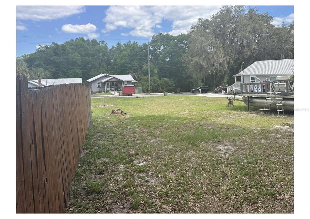 A grassy, fenced-in backyard lot with a boat on a trailer to the right — 1206 S 12TH STREET, PALATKA, FL