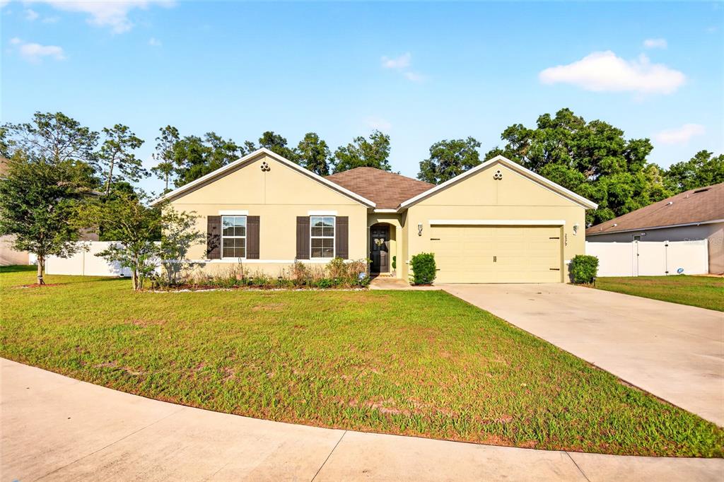 A single-story house with a beige stucco exterior, a two-car garage, and a front lawn — 2579 NE 46TH AVENUE, OCALA, FL
