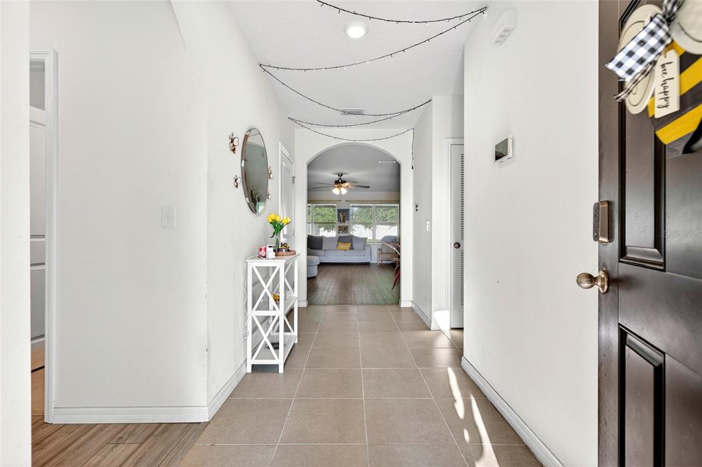 A tiled entryway leads through an arched doorway into a living room with wood flooring — 2579 NE 46TH AVENUE, OCALA, FL