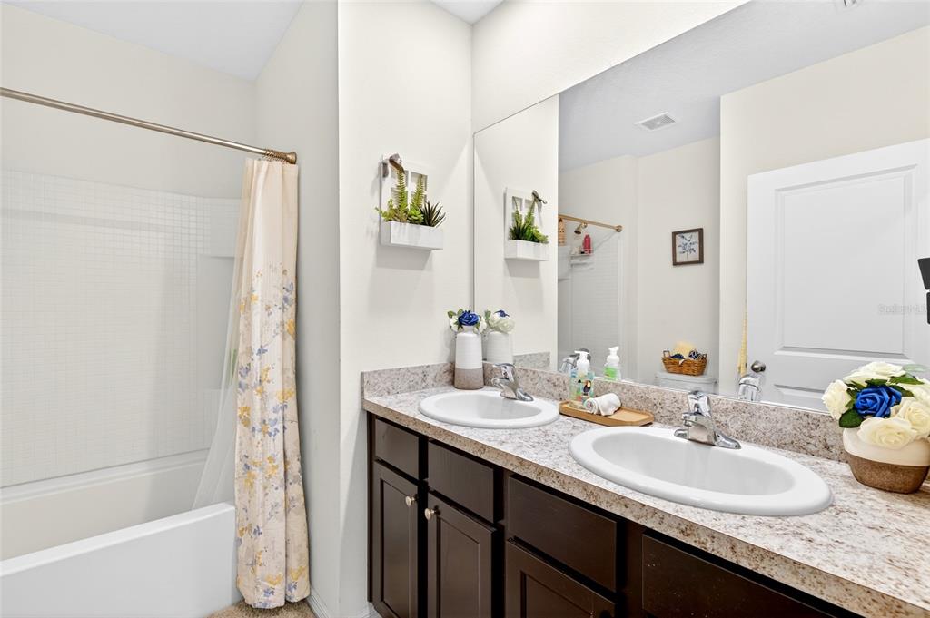 A bathroom features a double vanity with dark cabinets, granite countertops, and a shower-tub combo — 2579 NE 46TH AVENUE, OCALA, FL