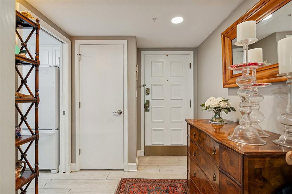 An entryway features a wooden dresser, a white door, and a tall decorative shelf — 36750 US HIGHWAY 19 N UNIT 16210, PALM HARBOR, FL