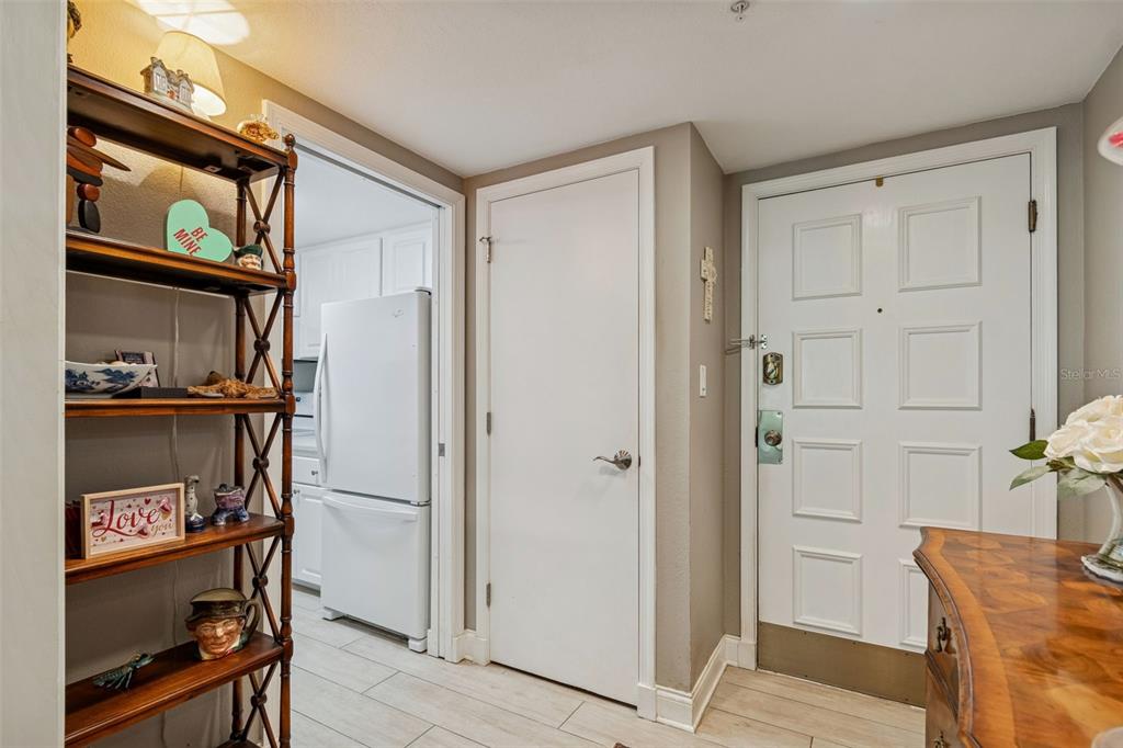 An entryway features a wooden shelf, a white door, and a view into a kitchen — 36750 US HIGHWAY 19 N UNIT 16210, PALM HARBOR, FL