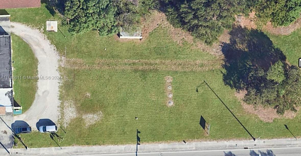 This aerial view shows a vacant, grassy rectangular lot bordered by a road and trees — 2065 NW 54th street, Miami FL 33142, MIAMI, FL