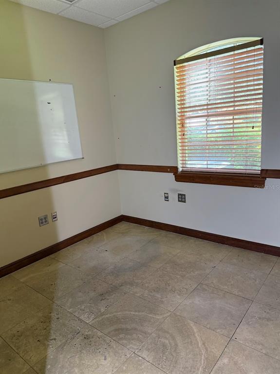 An empty office with beige tile flooring, a whiteboard, and a window with wood blinds — 1400 S US HWY 441, BUILDING 910 UNIT 912, LADY LAKE, FL