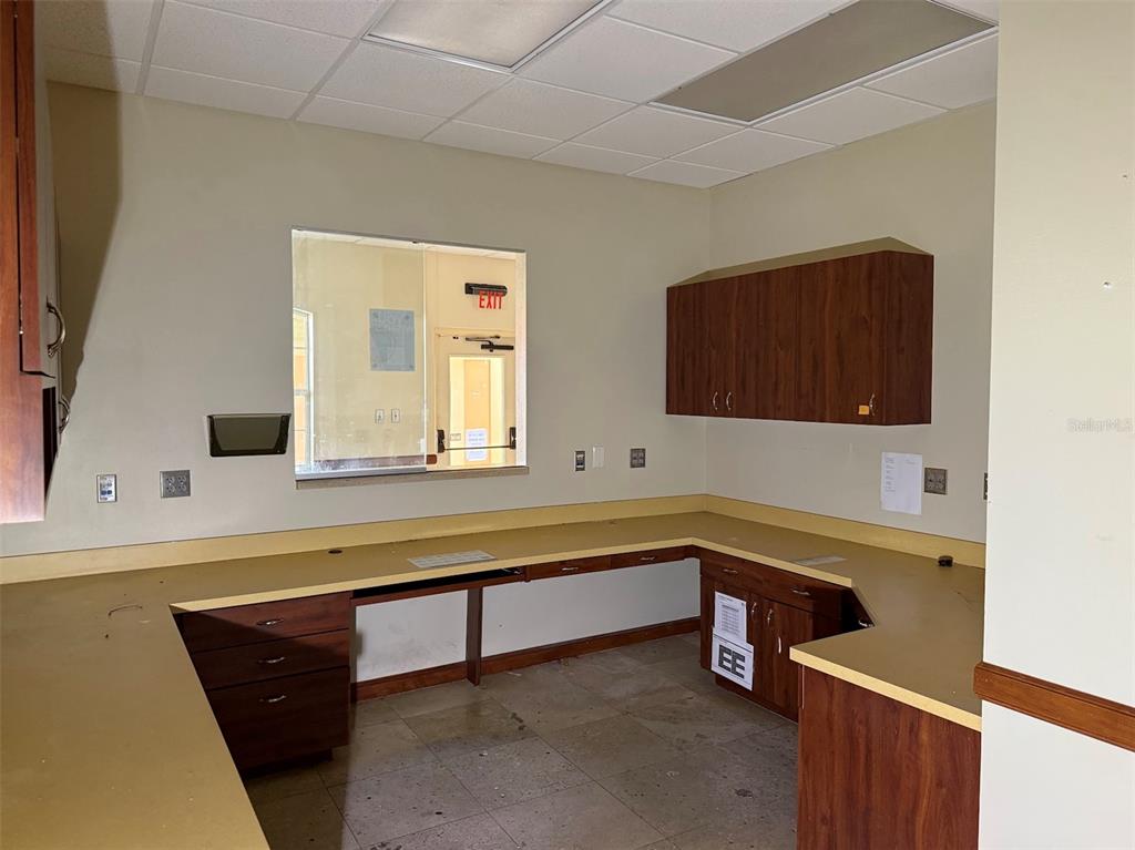 An office reception area features a U-shaped desk, wood cabinetry, and a pass-through window — 1400 S US HWY 441, BUILDING 910 UNIT 912, LADY LAKE, FL