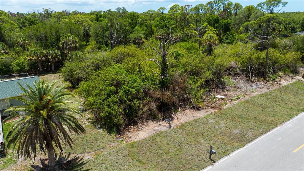 An aerial view shows a vacant, overgrown lot next to a house and a road — 12047 CHANCELLOR BOULEVARD, PORT CHARLOTTE, FL