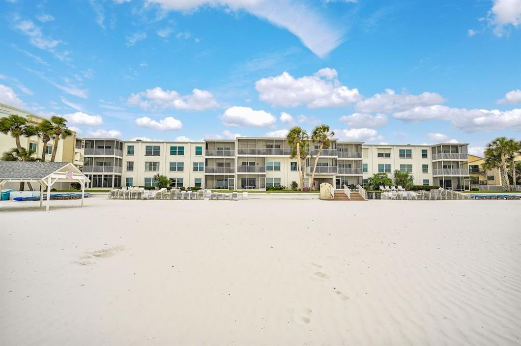A multi-story beachfront condominium building stands behind a wide expanse of white sand — 6154 MIDNIGHT PASS ROAD UNIT C09, SARASOTA, FL