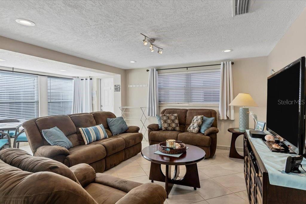 A living room features brown sofas, a round coffee table, and a television on a console — 6154 MIDNIGHT PASS ROAD UNIT C09, SARASOTA, FL