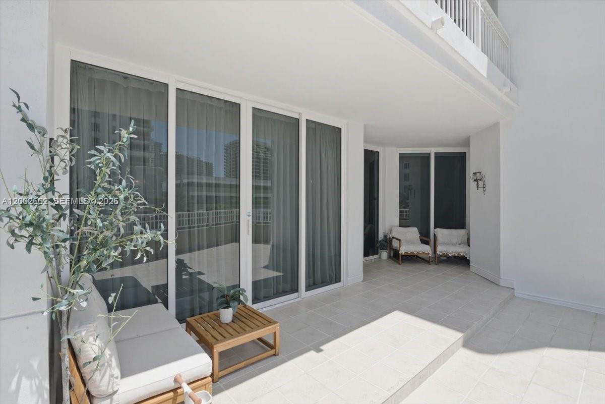 A covered balcony features white tile flooring, sliding glass doors, and outdoor seating — 801 Brickell Key Blvd # 409, Miami FL 33131, MIAMI, FL
