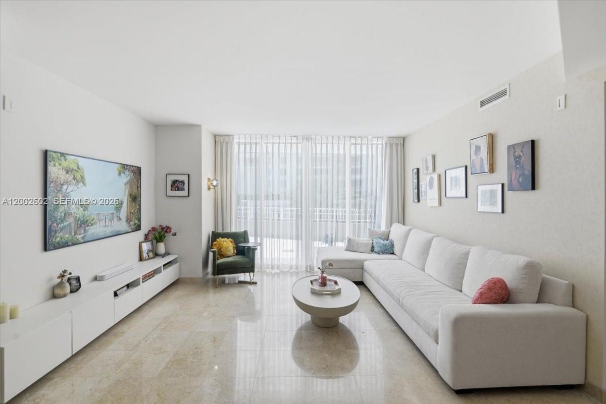 A living room features a white sectional sofa, a television, and floor-to-ceiling window curtains — 801 Brickell Key Blvd # 409, Miami FL 33131, MIAMI, FL