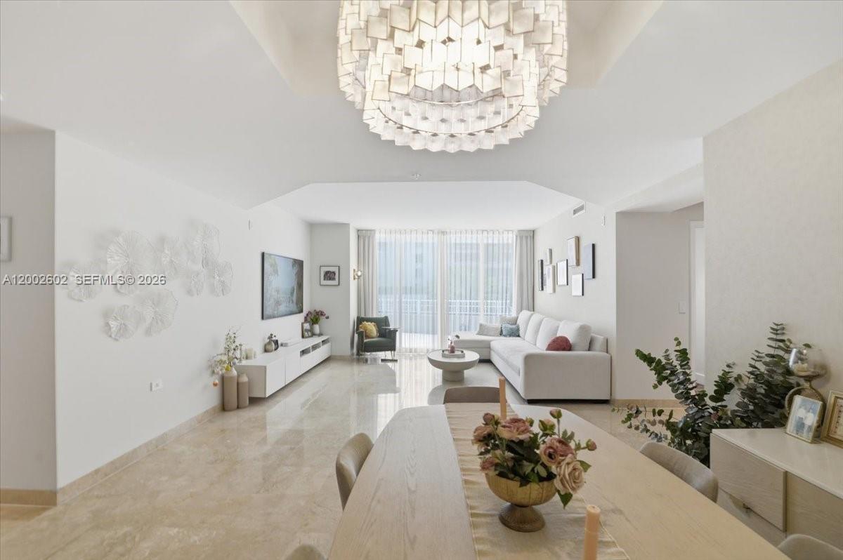 A bright living and dining area features marble floors, a large chandelier, and neutral furniture — 801 Brickell Key Blvd # 409, Miami FL 33131, MIAMI, FL