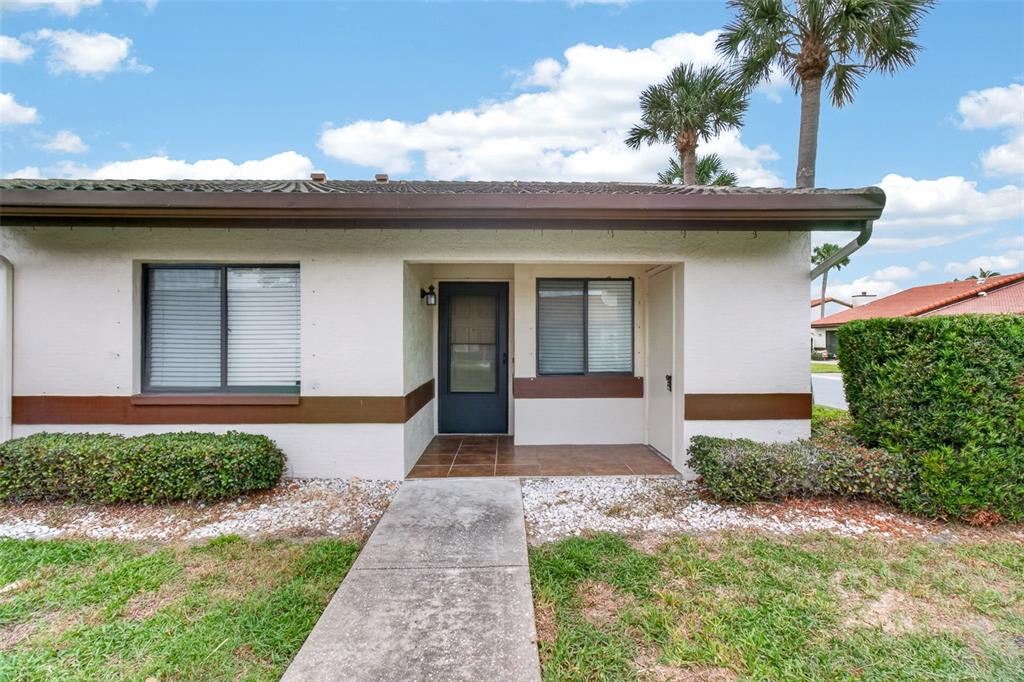 A single-story residential unit with a tiled entryway, brown trim, and a concrete walkway — 7360 ULMERTON ROAD UNIT 10D, LARGO, FL