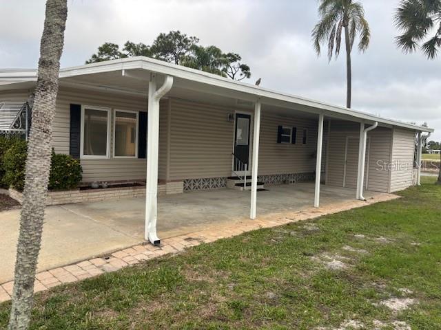 A single-story manufactured home features a covered carport, beige siding, and a brick-bordered walkway — 2100 KINGS HIGHWAY UNIT 781, PORT CHARLOTTE, FL