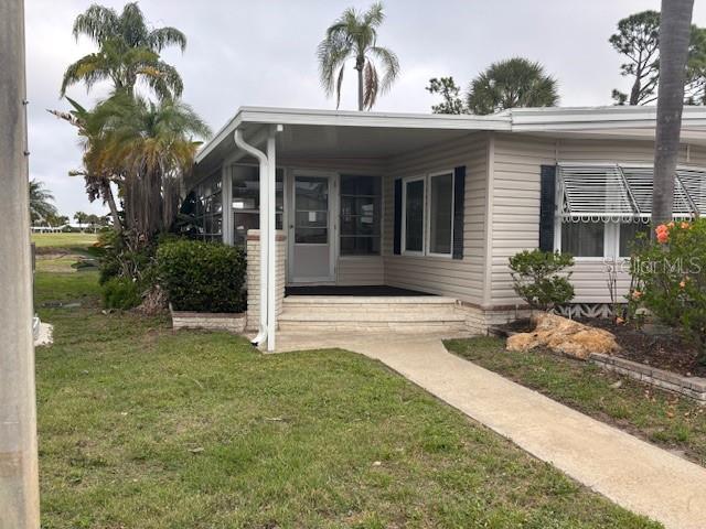 The exterior of a single-story manufactured home features a covered porch and a concrete walkway — 2100 KINGS HIGHWAY UNIT 781, PORT CHARLOTTE, FL