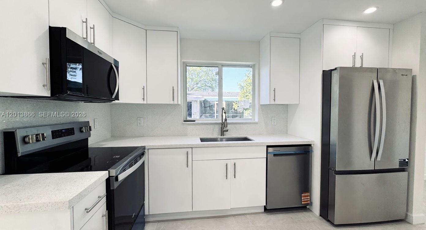 A modern kitchen features white cabinets, stainless steel appliances, and light-colored countertops — 8442 SW 107th St, Miami FL 33156, MIAMI, FL