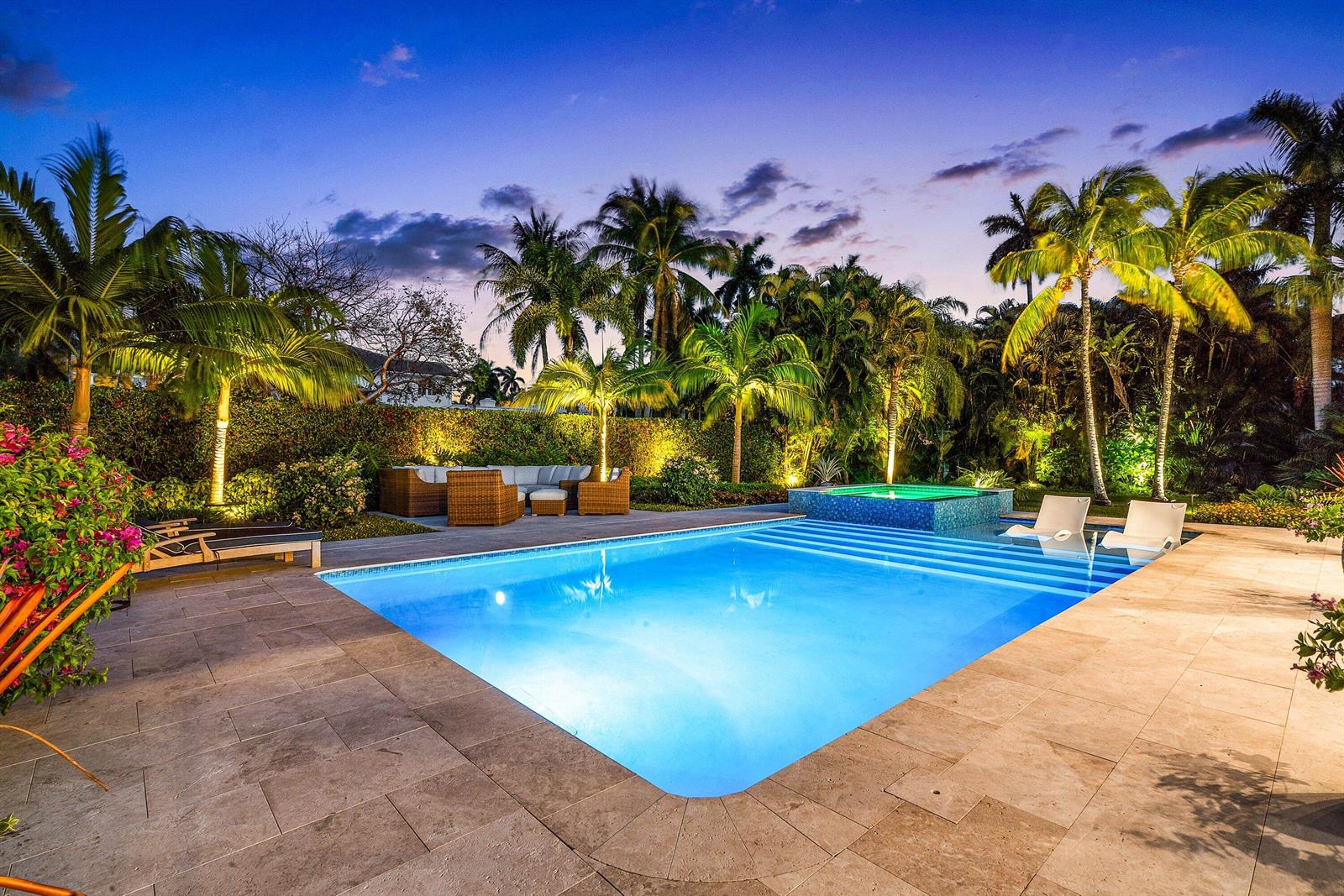 A swimming pool with an attached hot tub sits on a stone patio at dusk — 1101 Thomas Street, Delray Beach FL 33483, DELRAY BEACH, FL