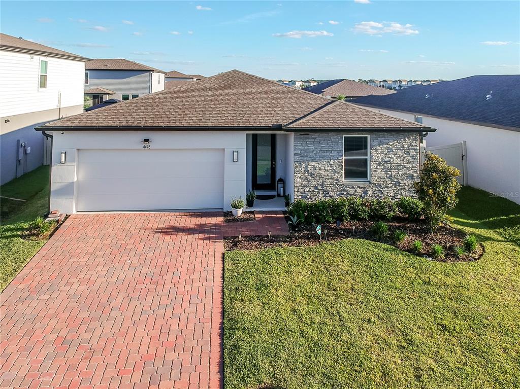 A single-story house with a brick driveway, stone facade, and a two-car garage — 4498 PICKEREL WEED, ST CLOUD, FL