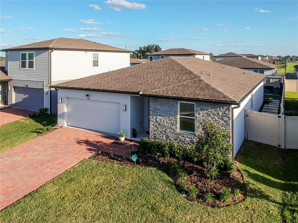 An exterior view of a single-story house with a stone facade and brick driveway — 4498 PICKEREL WEED, ST CLOUD, FL