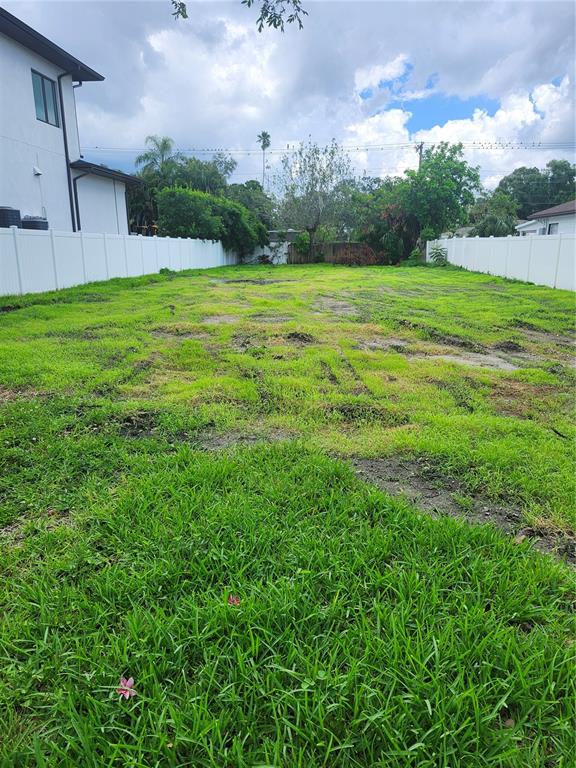 A long, narrow vacant lot with patchy grass is enclosed by white vinyl privacy fences — 507 DANUBE AVENUE, TAMPA, FL