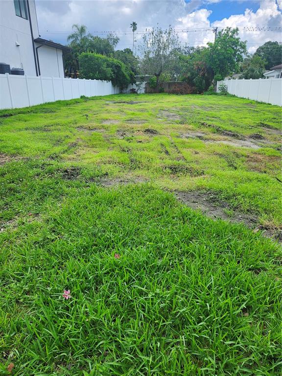 A long, narrow, grassy vacant lot is enclosed by white vinyl fences on both sides — 507 DANUBE AVENUE, TAMPA, FL