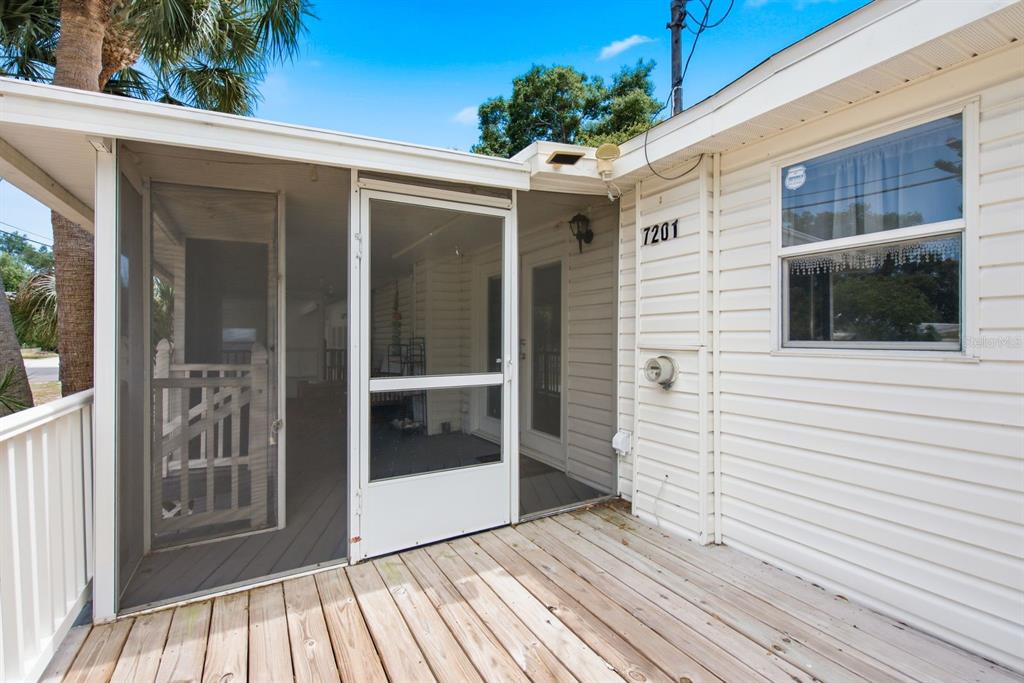 A wooden deck leads to a screened-in porch entrance on the side of a house — 7201 5TH AVENUE N, ST PETERSBURG, FL