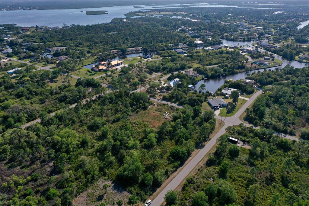 An aerial view shows a residential area with houses, canals, and dense vegetation — 12453 KOENIG LANE, PORT CHARLOTTE, FL