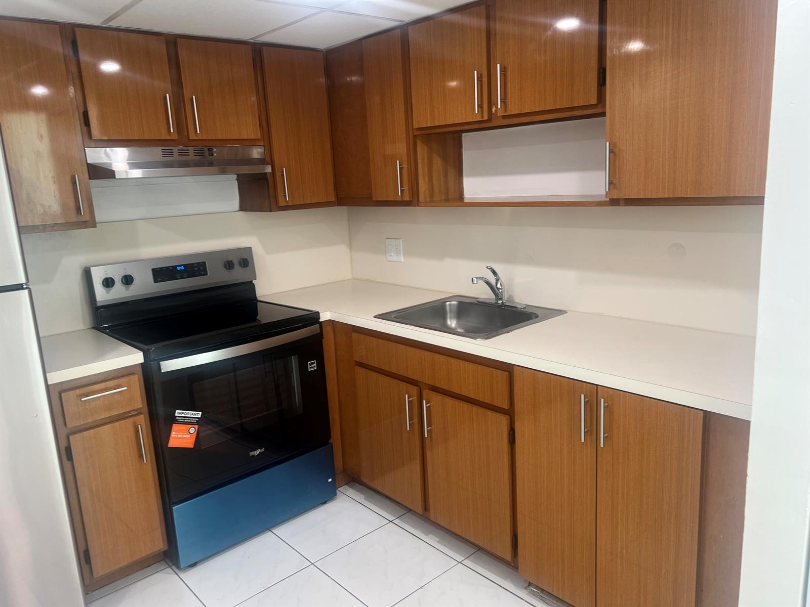 A kitchen features wood-grain cabinets, stainless steel appliances, white countertops, and white tile flooring — 2055 SW 122nd # 219, Miami FL 33175, MIAMI, FL