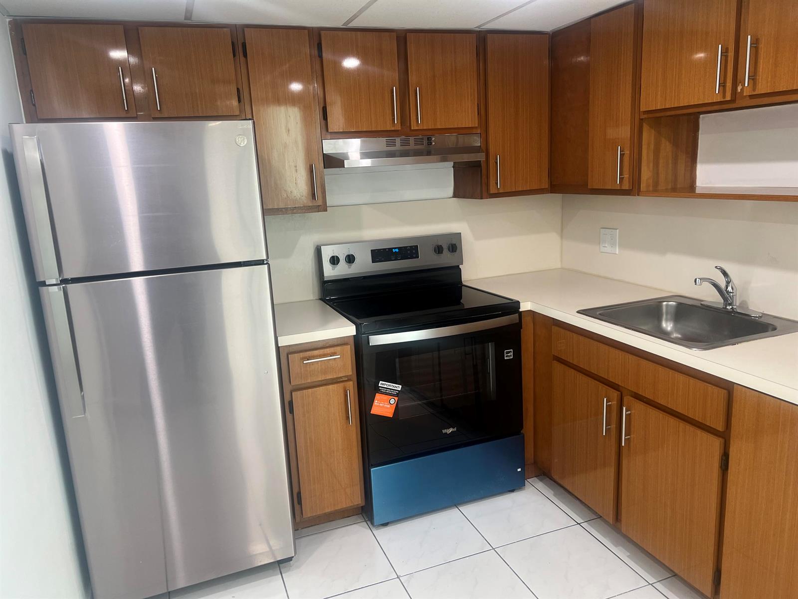 A kitchen features wood-grain cabinets, stainless steel appliances, white countertops, and white tile flooring — 2055 SW 122nd # 219, Miami FL 33175, MIAMI, FL