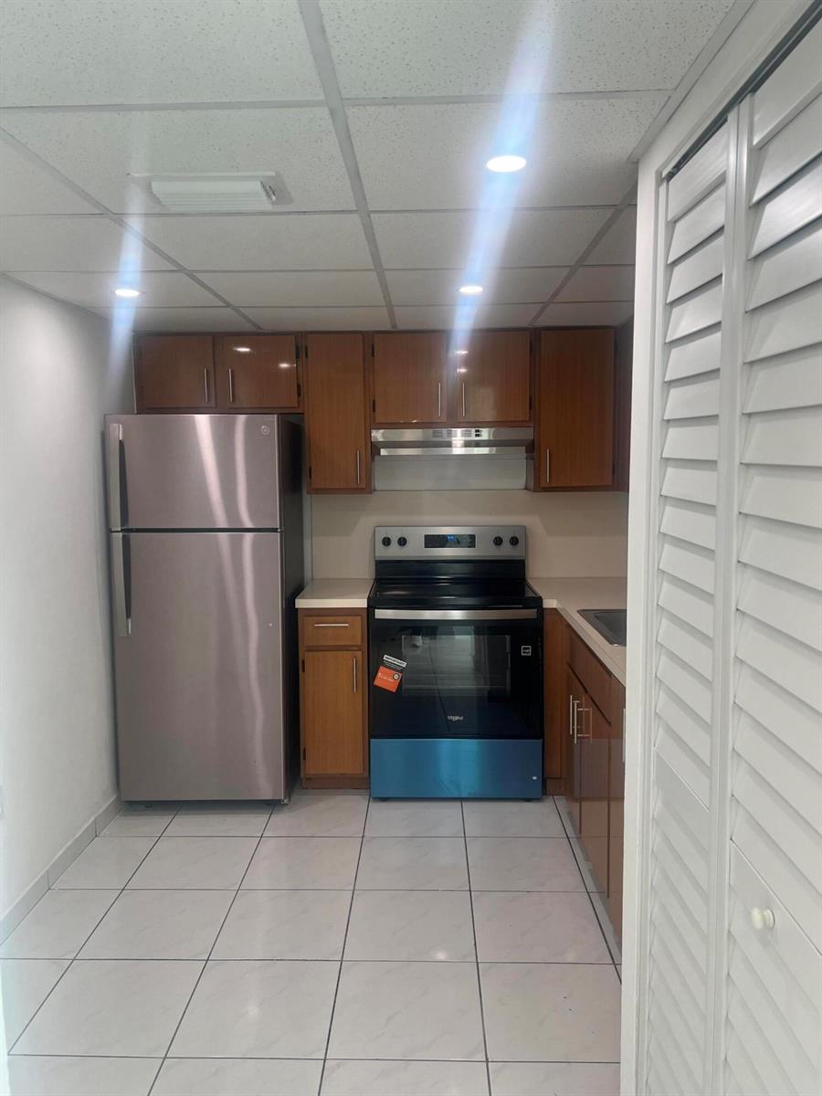 A kitchen with wood cabinets, stainless steel appliances, and white tile flooring — 2055 SW 122nd # 219, Miami FL 33175, MIAMI, FL